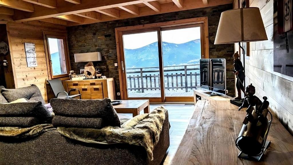 a living room with a couch and a large window at Chalet Cosy avec vue imprenable sur le lac in La Celle-sous-Gouzon