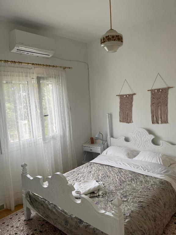 a white bedroom with a white bed and a window at Eva's house in Rafina