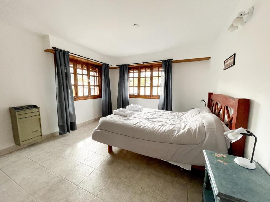 a bedroom with a bed and a desk and windows at Hermoso departamento en Esquel, amplio y luminoso in Esquel