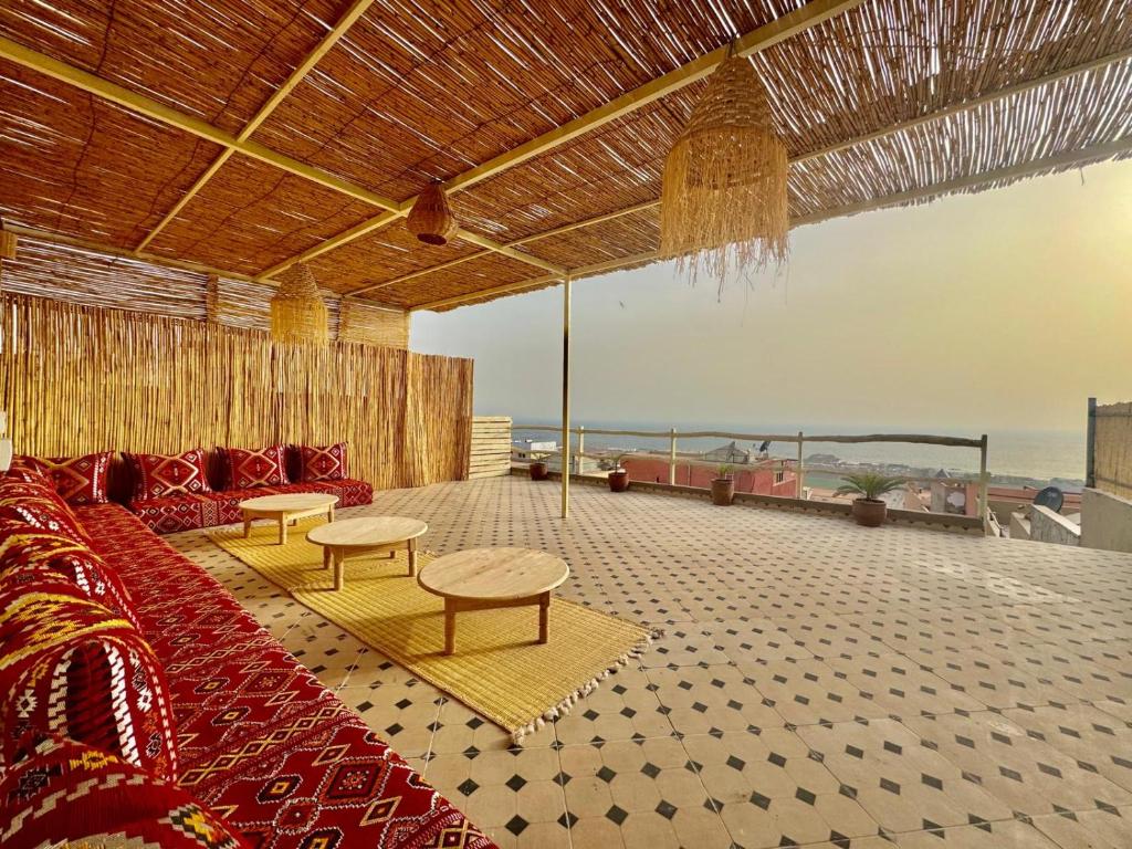 a living room with a couch and tables and the ocean at SurfsHub Hostel Tamraght in Tamraght Ouzdar