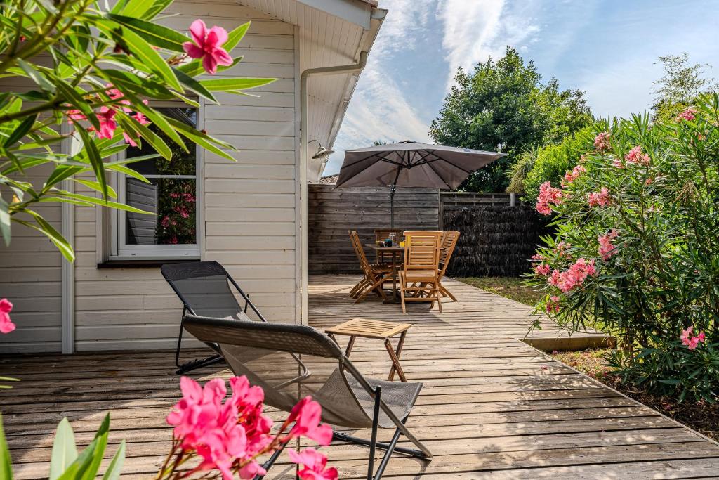 un patio avec une table, des chaises et un parasol dans l'établissement Pretty wooden house with terrace - Bassin d'Arcachon, à Arès
