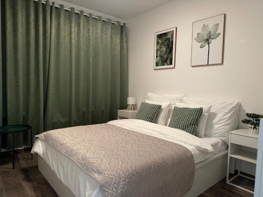 a bedroom with a large bed with green curtains at Cozy Modern Apartment, 20 mins to Center in Prague
