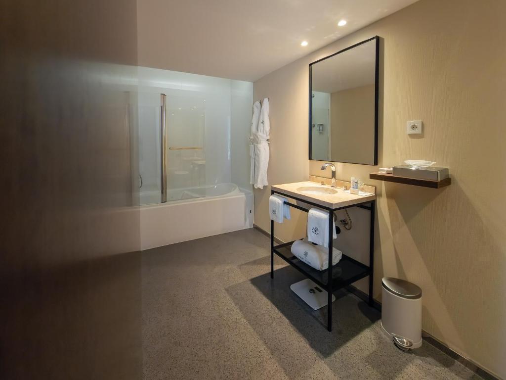 ein Badezimmer mit Waschbecken, Spiegel und Badewanne in der Unterkunft Lisboa Carmo Hotel in Lissabon