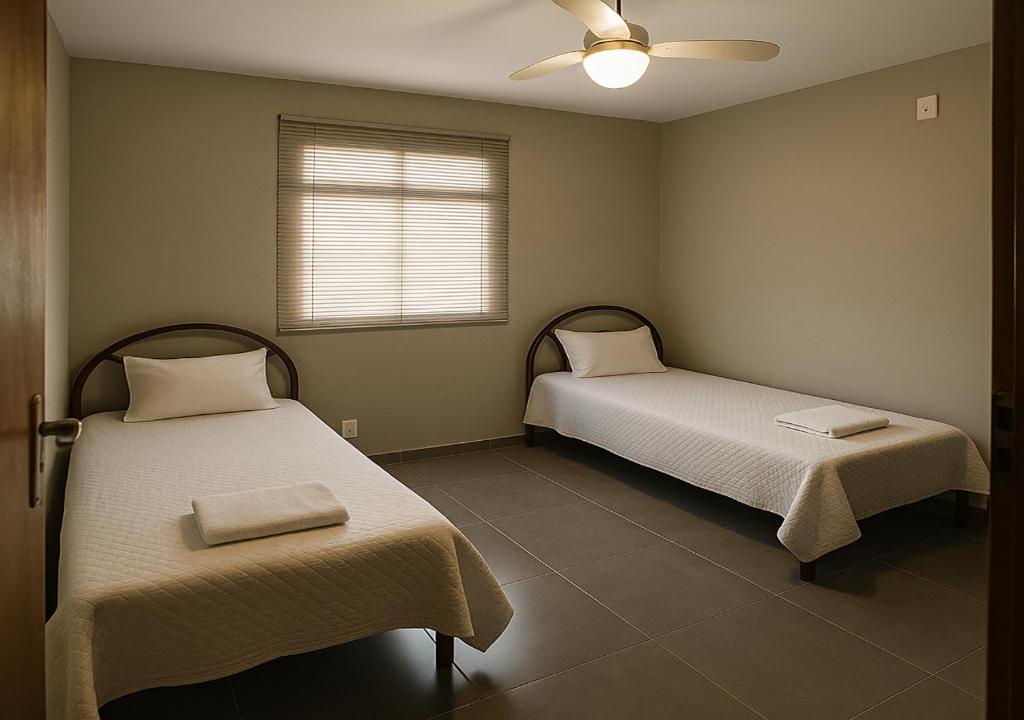 een kamer met twee bedden en een raam bij Cobertura - Praia do Morro in Guarapari