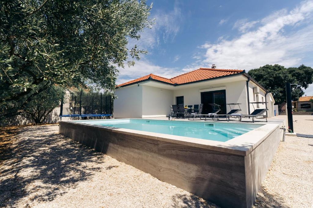 a swimming pool in front of a house at Martha's Oliveyard in Biograd na Moru