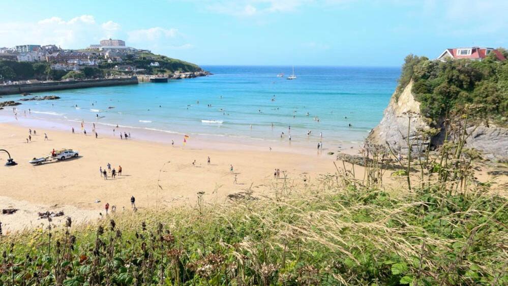 ニューキーにあるModern surf pad, steps from Towan beachの海の近くのビーチにいる人々のグループ
