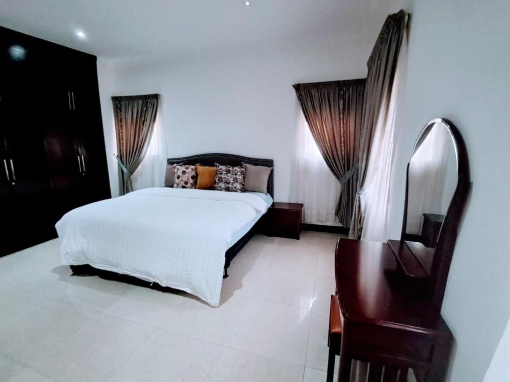 a bedroom with a bed and a mirror and a chair at Stylish 3 bedroom House Near Airport & Marina Mall in Accra