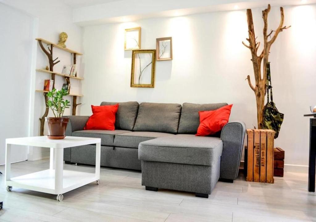 - un salon avec un canapé gris et des oreillers rouges dans l'établissement Arc & Peyrou Évasion, Montpellier, à Montpellier