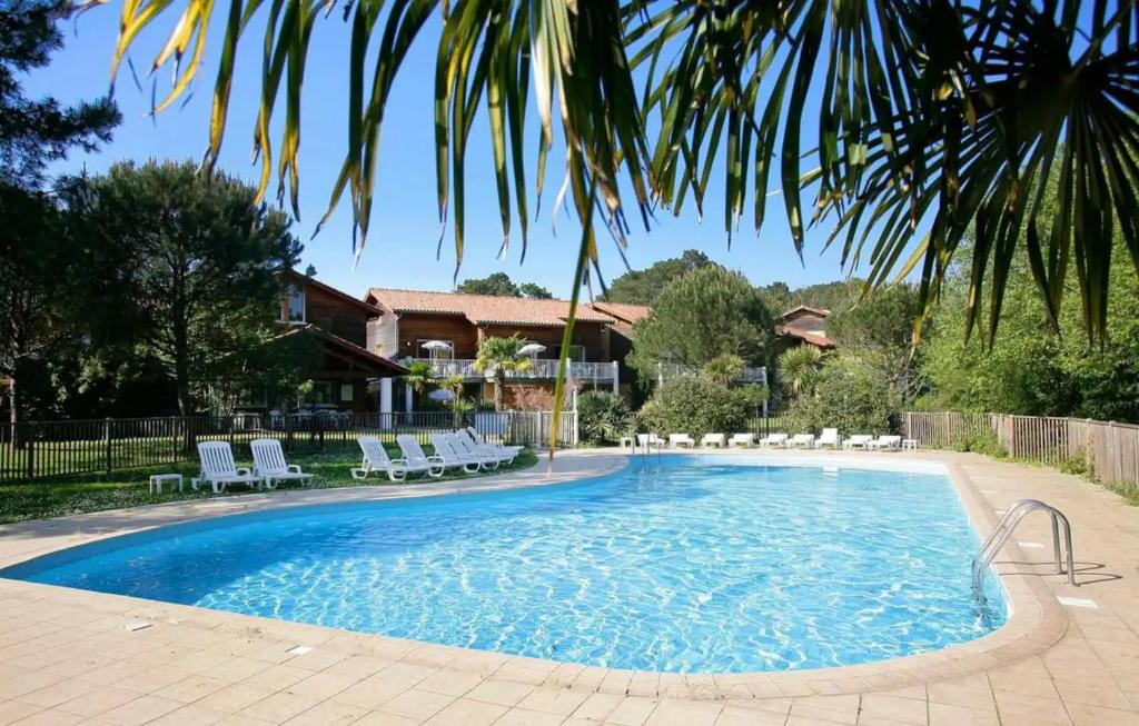 a large swimming pool with chairs and a house at Appartement 52 4-6 personnes plages à pied in Capbreton