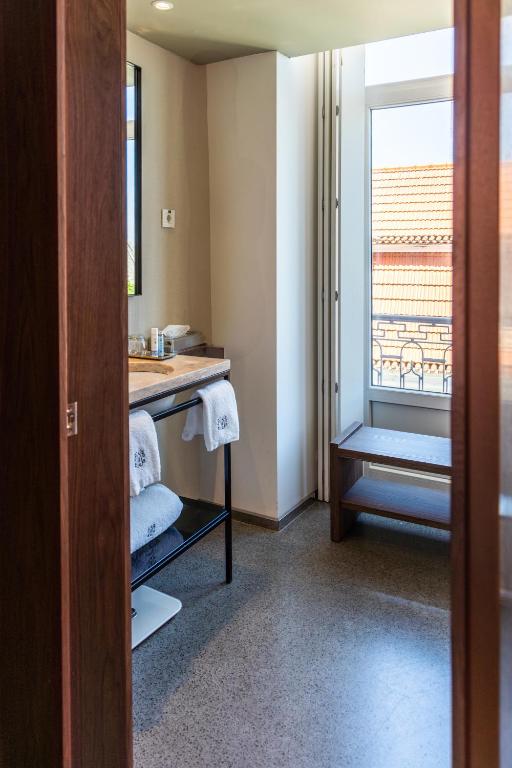 A compact bathroom with a vanity, towel storage and a large window seat.