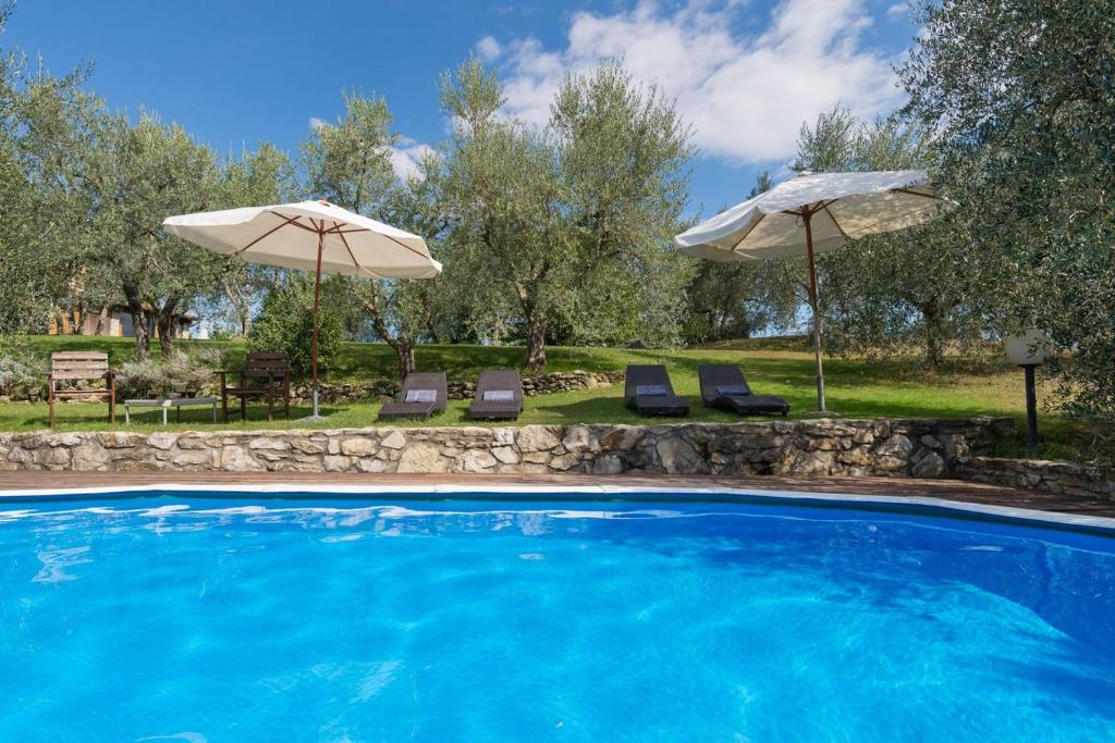 a swimming pool with two umbrellas and two chairs at La Sassaia in Carmignano