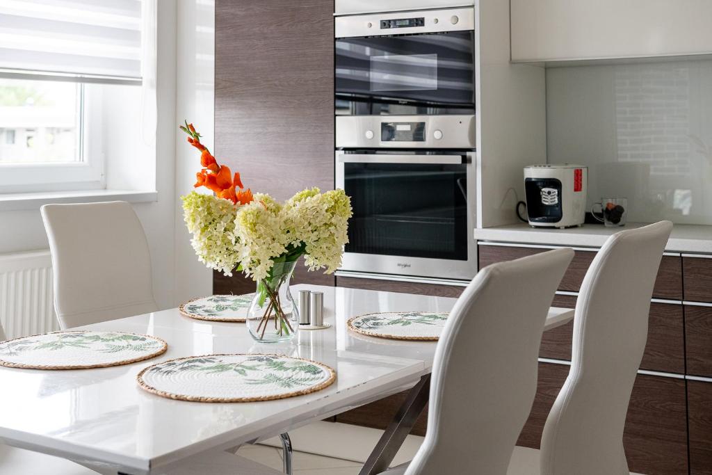 a white table with chairs and a vase of flowers at White City Apartman- with free garage in Nyíregyháza