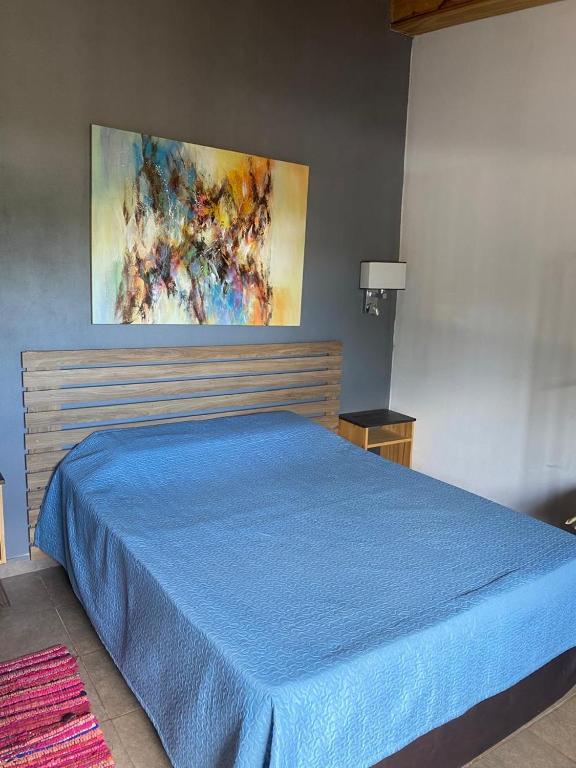 a blue bed in a bedroom with a painting on the wall at Monoambiente en posadas in Posadas