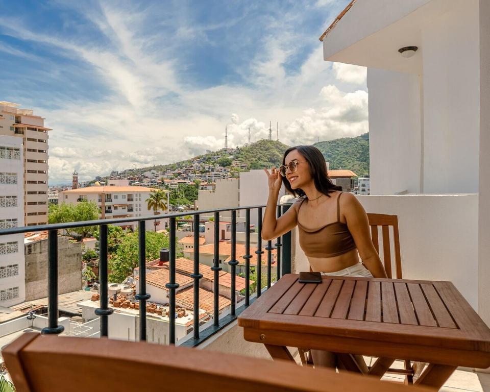 Eine Frau im Bikini, die an einem Tisch auf einem Balkon sitzt. in der Unterkunft Casa Brisa in Puerto Vallarta