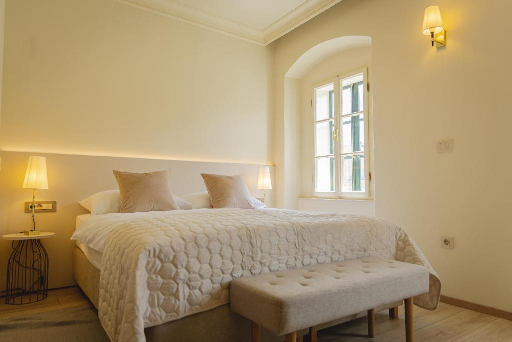 een witte slaapkamer met een bed en een raam bij Vogel Rooms Tvrđa Osijek in Osijek