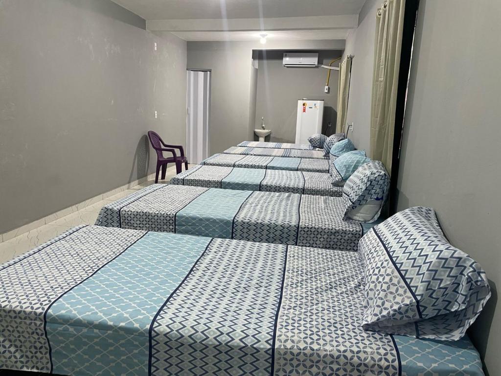 four beds lined up in a row in a room at Hostel do Porto in Queimada