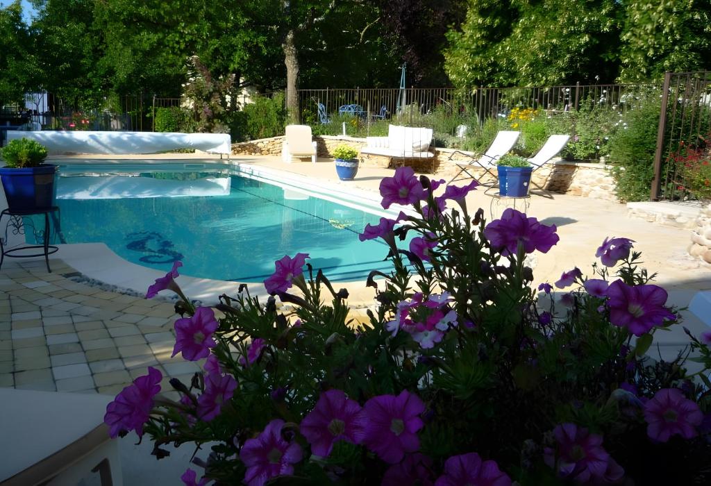 a swimming pool with purple flowers in front of it at Gite La Bastide De La Coda in Châteauneuf-du-Rhône