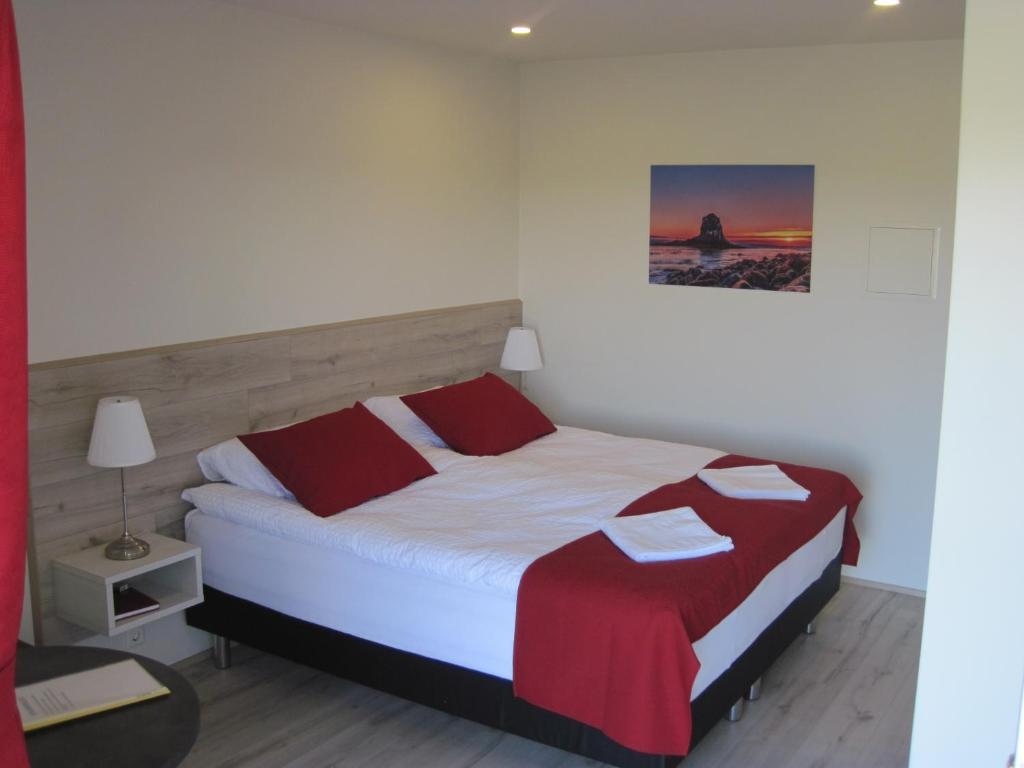 a bedroom with a bed with red and white sheets at Skógar Sunset Guesthouse in Húsavík