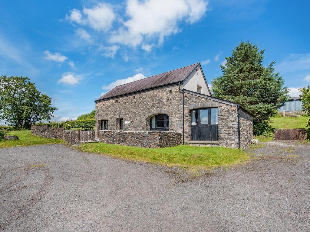 an old stone house with a gravel driveway at Rhandir Barn in Ffair-fâch