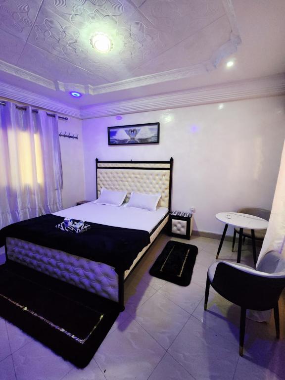 Un dormitorio con una cama, una mesa y una silla. en Chambre Meublé avec Toillette intérieure chauffe eau Wi-Fi Smart Tv, en Dakar