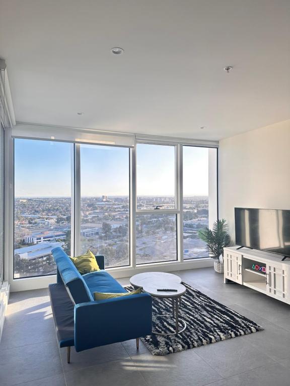 a living room with a blue couch and large windows at Luxurious city view at Sydney Olympic Park in Sydney