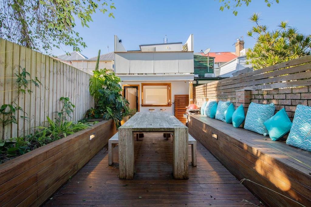 a wooden patio with a table and blue pillows at Casa Dianna - Timeless Terrace near CBD and Waterfront in Newcastle