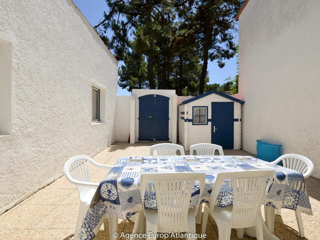 une table avec des chaises blanches et un chiffon de table bleu et blanc dans l'établissement Maison 3 chambres à La Palmyre - Près de la mer, Parking, WIFI, Animaux admis - FR-1-705-14, à La Palmyre