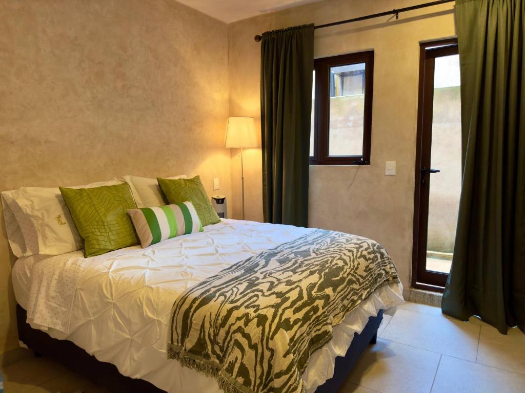 Un dormitorio con una cama con almohadas verdes y una ventana. en Valeria en ValQuirico, en Santeagueda