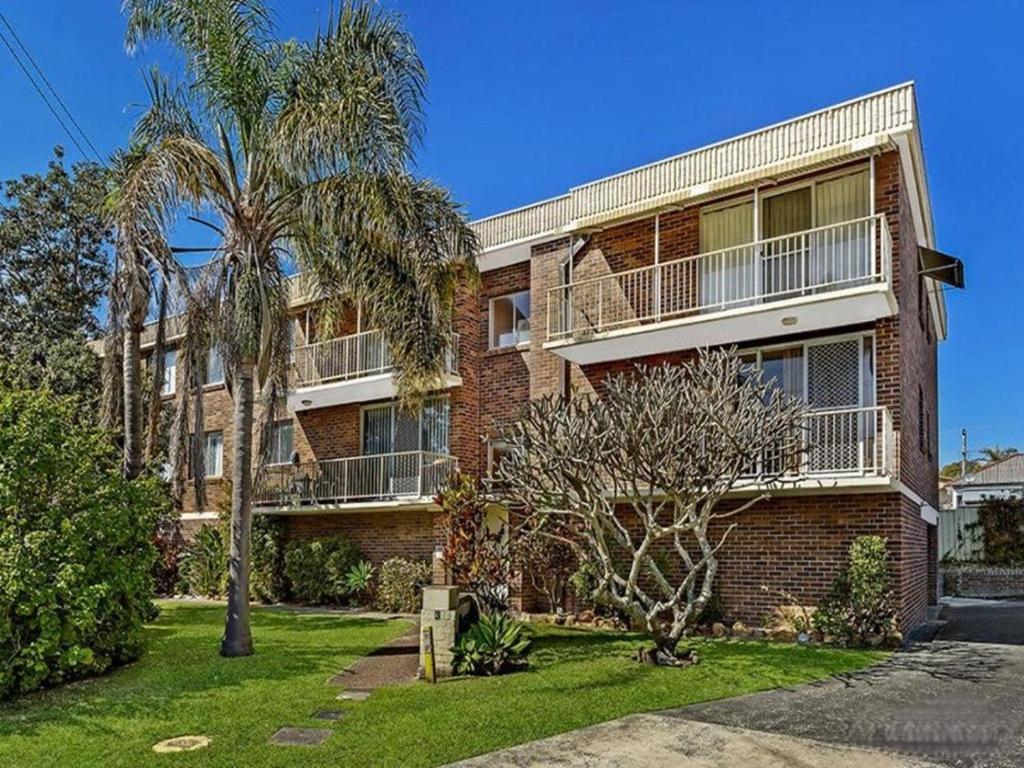 a brick apartment building with a balcony and palm trees at Cul-de-Sac Cove, Unit 4 in The Entrance
