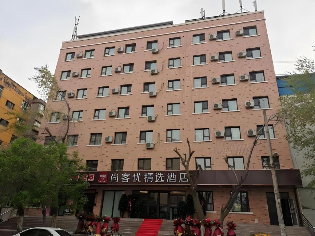 a large brick building with people in front of it at Thank Inn Plus Hotel Xinjiang Urumqi Tianshan District Bingtuan Erzhong in Ürümqi