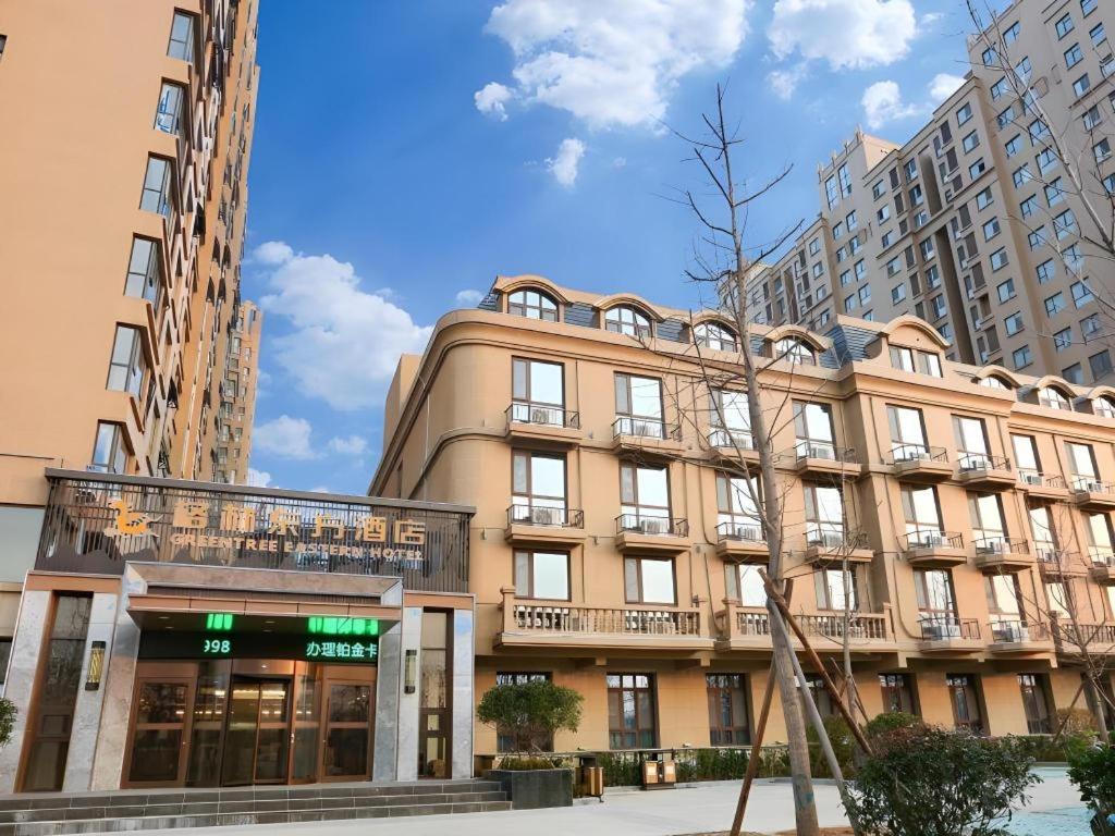 a large building in a city with tall buildings at GreenTree Eastern Hotel Linyi Linshu County Aegean Sea in Linyi