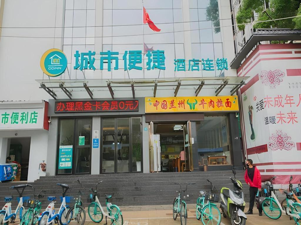 une femme debout devant un bâtiment avec des vélos garés à l'extérieur dans l'établissement City Comfort Inn Nanchang Bayi Square Metro Station Wushang, à Nanchang