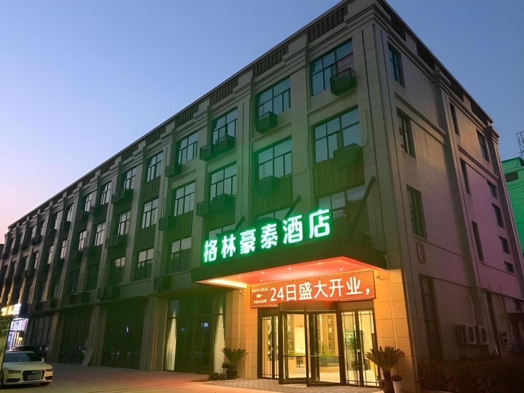 un bâtiment avec des panneaux de néon sur son côté dans l'établissement GreenTree Inn Jiangsu Nantong Rudong County Changsha Town Government, à Jinjiazhuang