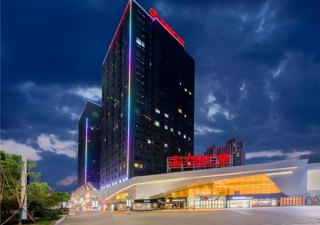 a tall building is lit up at night at City Comfort Inn Shiyan High-speed Railway Wanda Plaza in Shiyan