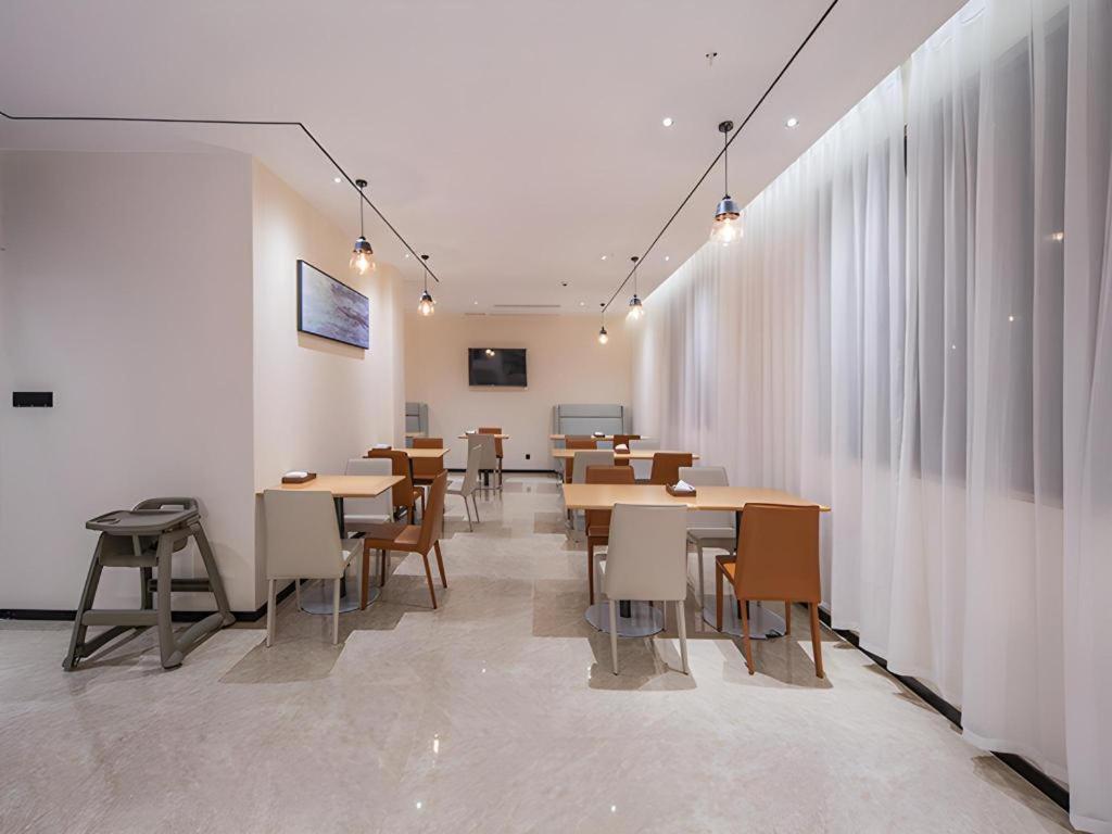 ein Esszimmer mit Tischen und Stühlen und Fenstern in der Unterkunft City Comfort Inn Fangchenggang Government Affairs Center in Fangchenggang