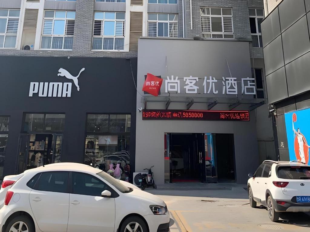 deux voitures blanches garées devant un bâtiment dans l'établissement Thank Inn Hotel Shandong Heze Mudan District Bayi Road Pedestrian Street, à Zhaolou