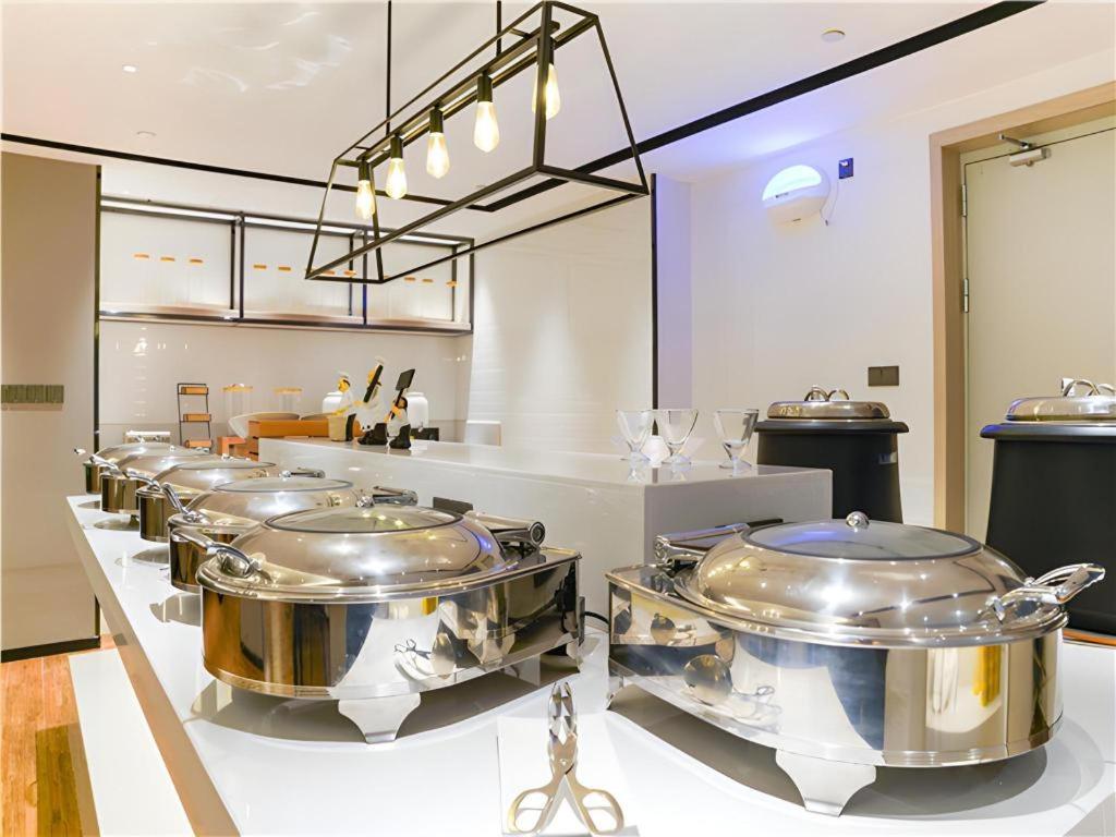 a row of large stainless steel pots in a kitchen at Echarm Hotel Suzhou Shengze Oriental Extile City in Suzhou
