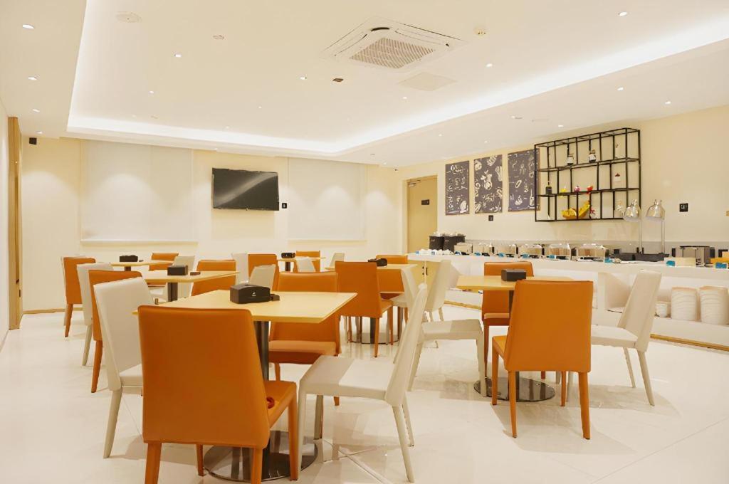 une salle à manger avec des tables et des chaises en bois dans l'établissement City Comfort Inn Zhanjiang International Trade Dingsheng Plaza, à Zhanjiang