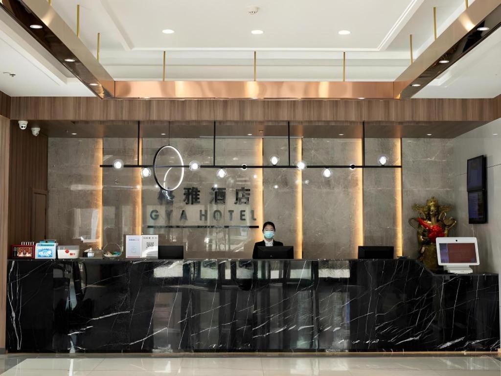 a man sitting at a counter in a hotel lobby at Gya Hotel Tangshan Qian'an Fortune Center in Qian'an