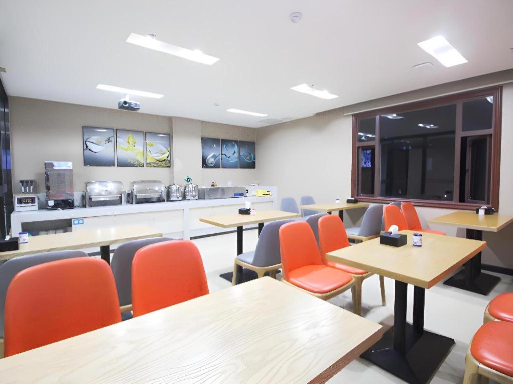 a restaurant with tables and chairs and a kitchen at City Comfort Inn Huizhou Zhongkai Huitai Industrial Park in Huizhou