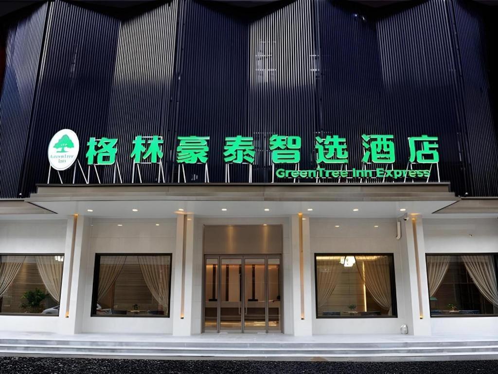 a building with green and white signs on it at Green Tree Inn Express Shandong Dezhou Qihe County Qiqifa in Sangzidian