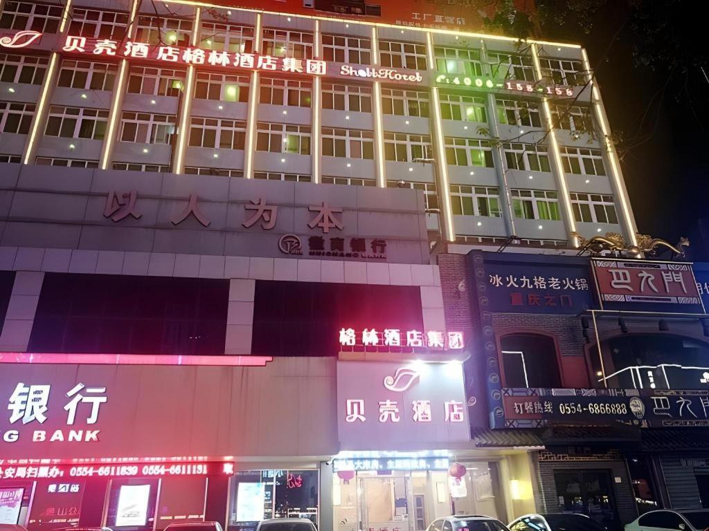 HuainanにあるShell Hotel Anhui Huainan Tianjia'an District Longhu Nan Roadの側面にネオンサインがある建物