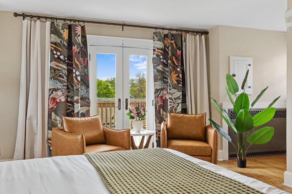 ein Schlafzimmer mit einem Bett und zwei Stühlen und einem Fenster in der Unterkunft ArtGallery PrivateHotTub Sauna NearMountRushmore FamilyHome in Rapid City