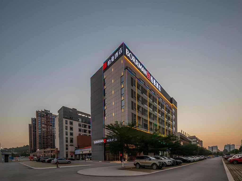 un grand bâtiment avec des voitures garées dans un parking dans l'établissement Borrman Hotel Chongzuo Guangxi Normal University for Nationalities, à Buli