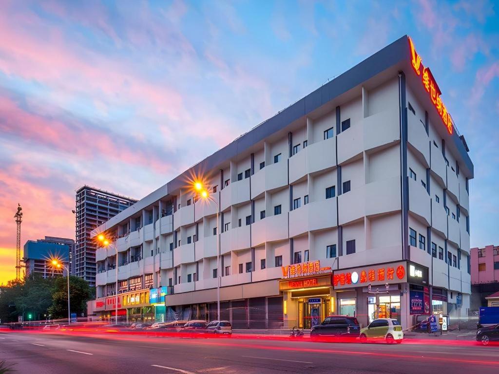 a large white building with cars parked in front of it at Vienna Hotel Tianjin Chentangzhuang Metro Station in Tianjin