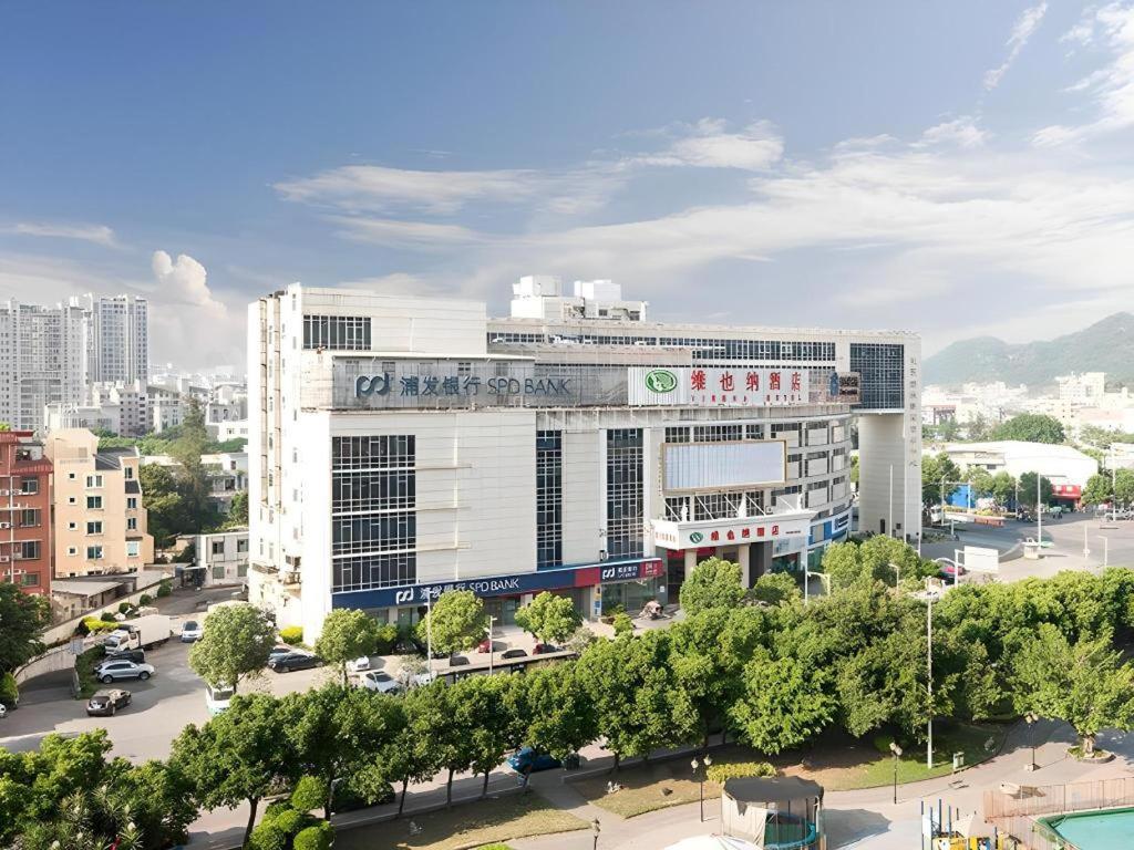 a large white building in a city with a street at Vienna Hotel Fuzhou Changle Zhenghe Metro Station in Fuzhou