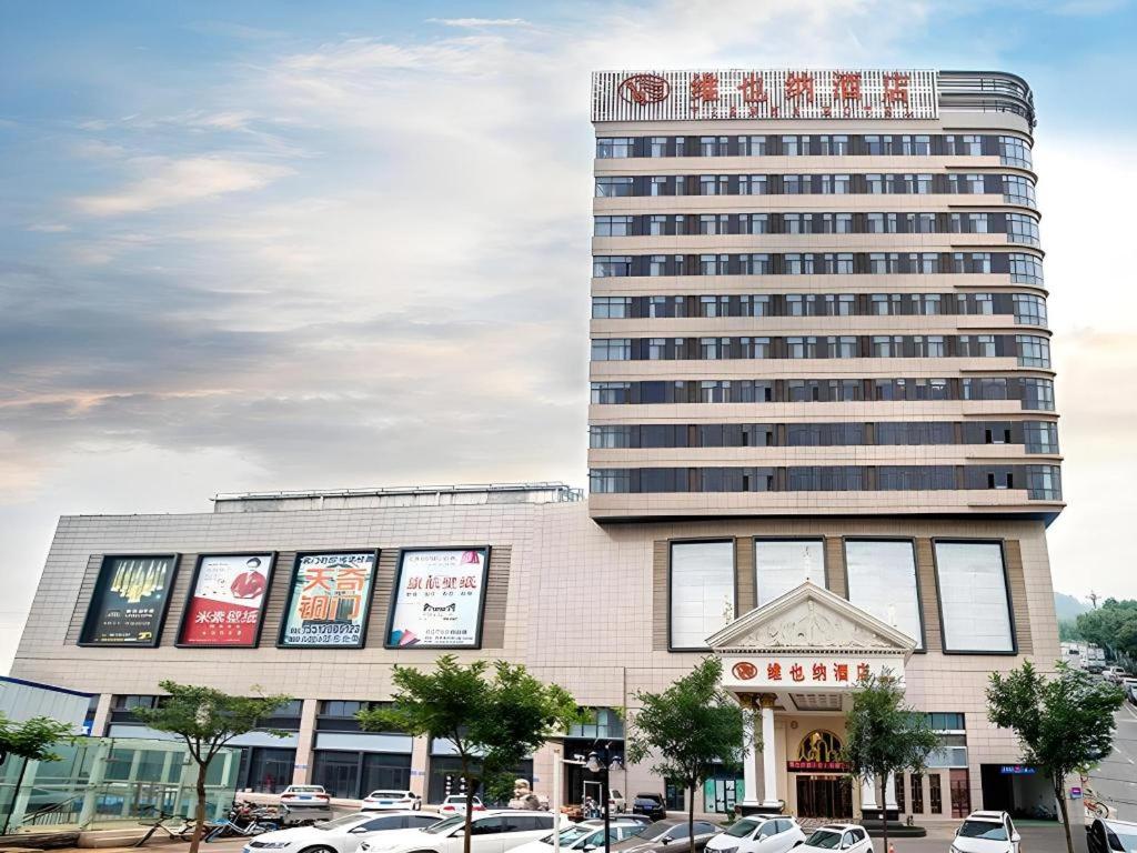 un grand bâtiment avec une enseigne au sommet dans l'établissement Vienna Hotel Hebei Tangshan Nanhu Park, à Tangshan