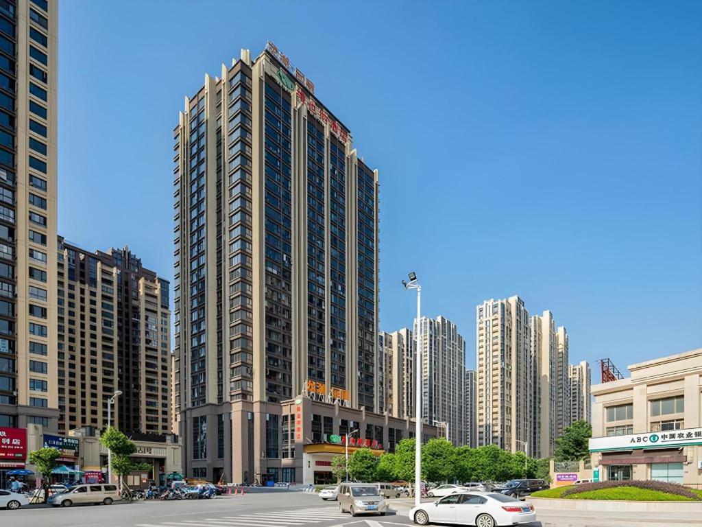a tall building with cars parked in a city at Vienna Hotel Fuzhou Changle Shouzhan Hangcheng Metro Station in Fuzhou