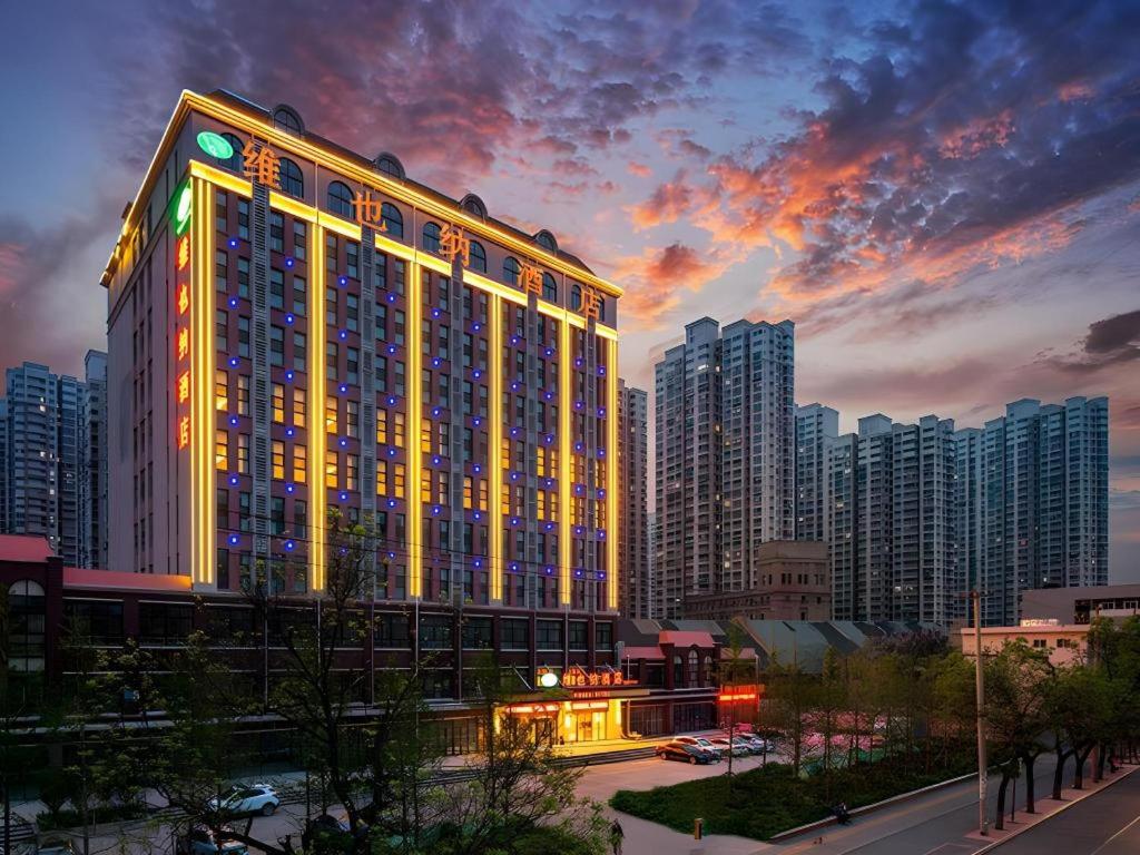 a large building with lights on it in a city at Vienna Hotel Jinan Railway Station in Jinan