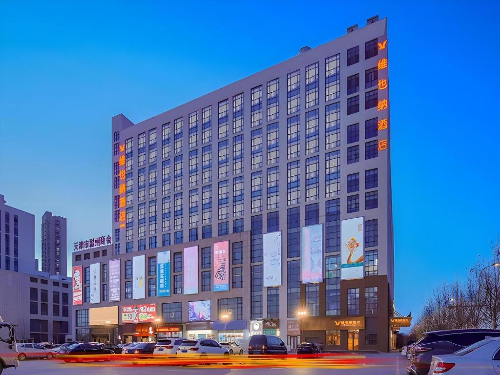 a large building with cars parked in a parking lot at Vienna Hotel Tianjin Jinzhong Street in Tianjin